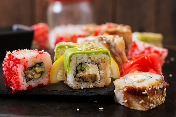 Traditional Japanese food - sushi, rolls and sauce on a black background.