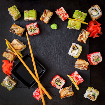 Traditional Japanese food - sushi, rolls and sauce on a black background. Top view