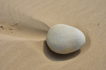 Fototapeta na wymiar Eiförmiger Stein auf Sandstrand