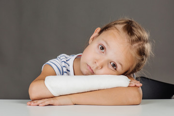 Smiling  girl with broken arm  is standing and looking at the camera