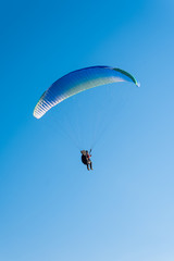 Paragliding in the sky. Man flying a paraglider on the sun.