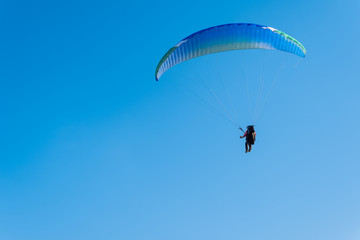 Paragliding in the sky. Man flying a paraglider on the sun.