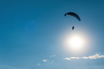 Paragliding in the sky. Man flying a paraglider on the sun.