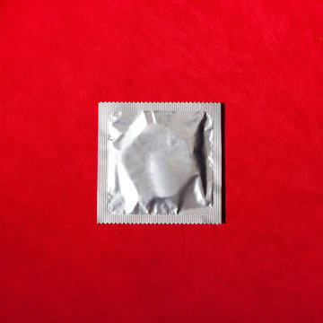Condom on red textile background