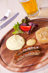 zwei Bratwürste auf einem Holzteller
