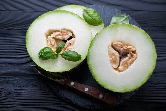 Ripe sliced melon on a black wooden background, close-up