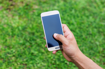 hand using a phone on a grass background.