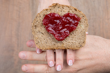 Toast bread with jam shape of hearts, vintage wooden table.