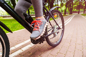 Close-up image of cyclist man feet riding mountain bike on trail in summer