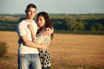 young couple posing on wheat field background, romantic and tenderness concept, summer season