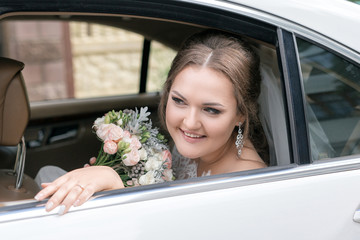 beautiful bride with bouquet in the car