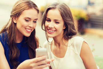 happy young women with smartphone at outdoor cafe