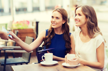 women paying money to waiter for coffee at cafe