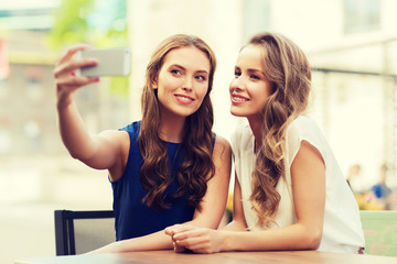 happy women with smartphone taking selfie at cafe