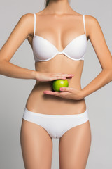 picture of  woman holding  green apple in front  her fit belly in white lingerie or underwear fashion and beauty spa massage