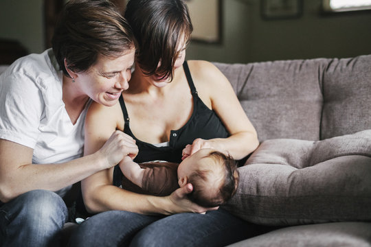 A same sex couple, two women playing with their 6 month old baby girl. 
