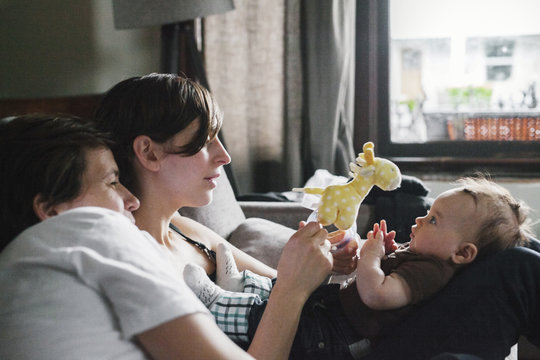 A same sex couple, two women playing with their 6 month old baby girl. 