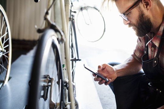 A bike mechanic in a bicycle repair shop using a smartphone
