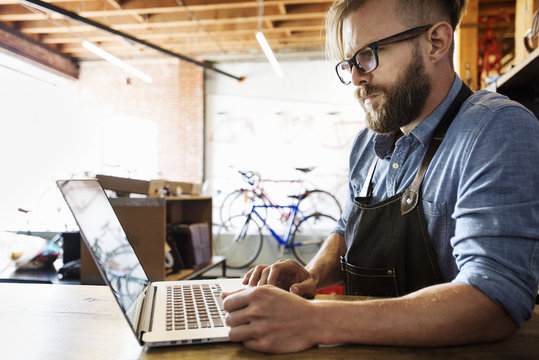 A man in a bicycle repair shop using a laptop computer.  Running a business.