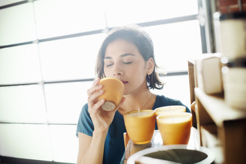 Young woman in a shop, smelling a scented candle.