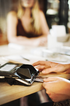 Close up of a woman using a credit card reader in a shop.