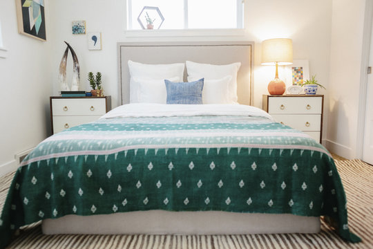 A bedroom in an apartment with a double bed  and a jade green patterned bed cover.