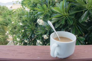Coffee cup with coffee spoon on the wooden balcony with sunlight in the morning and nature...