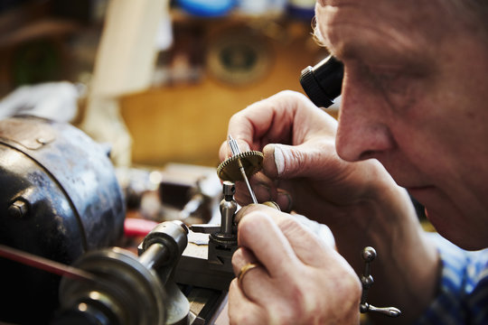 A clock maker busy in his workshop. 
