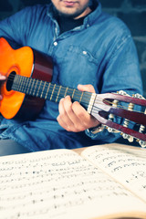 Young man playing on a guitar.