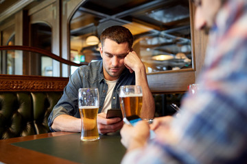 men with smartphones drinking beer at bar or pub