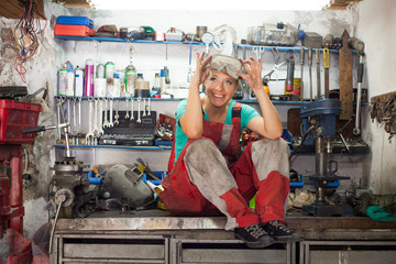 young woman posing in a mechanic shop - obrazy, fototapety, plakaty