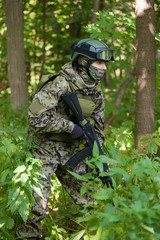 a man in a military uniform in the woods with a gun