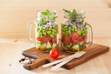 healthy vegetable salad in mason jar: tomato, cucumber, soybean,