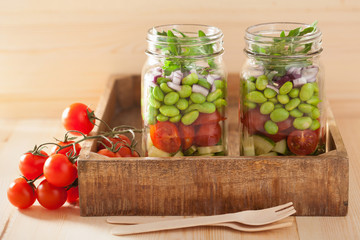 healthy vegetable salad in mason jar: tomato, cucumber, soybean,