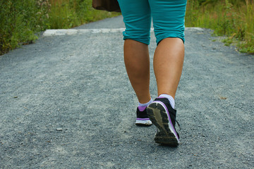 Back view of female legs with sport shoes  walking on a gravel trail