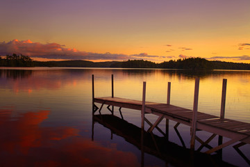 Fototapeta na wymiar old pier in a lake at the sunset in maine - united states of america