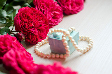 Cute small gift box with beads and bouquet of roses. Romantic decor elements