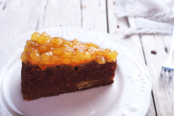 Close up of apple cake topping with apple sauce on a white plate.