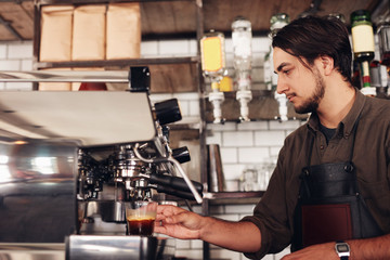 Fototapeta na wymiar Male barista preparing espresso at coffee shop