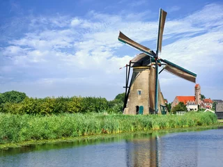 Foto op Plexiglas Molens Oude windmolen weerspiegeld in blauwe gracht op een zomerdag, Kinderdijk, Nederland.