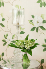Small bouquet of Lily of the valley flowers standing on decorative metallic table. Flower decor idea. Flower design. © aleksred