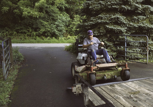 Man loading lawnmower on trailer