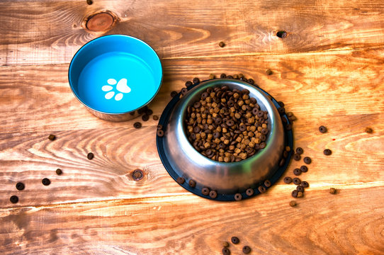 Full dog's bowls on wooden background