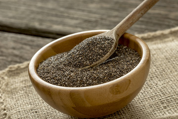 Spoon in round wooden bowl with chia seeds