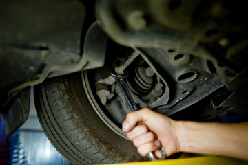Element of Auto mechanic working underneath a lifted car
