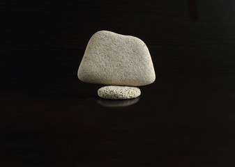 a set of smooth stones on a black background, stacked in the order