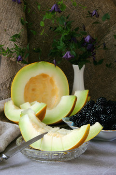 Ripe slices of melon and a plate with blackberries..