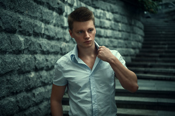 Obraz premium The guy in a shirt on a background of a stone wall