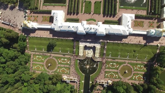 Top aerial view of beautiful Peterhof palace and grand cascade. Sparkling fountains. Golden statues. Unique aerial drone flight. Warm sunny day. 4K footage