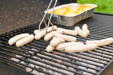 Sausage, hot dogs and potatoes on grill